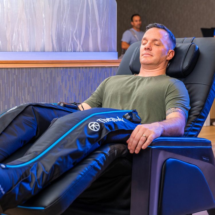 man sits in a compression therapy chair at brick bodies padonia