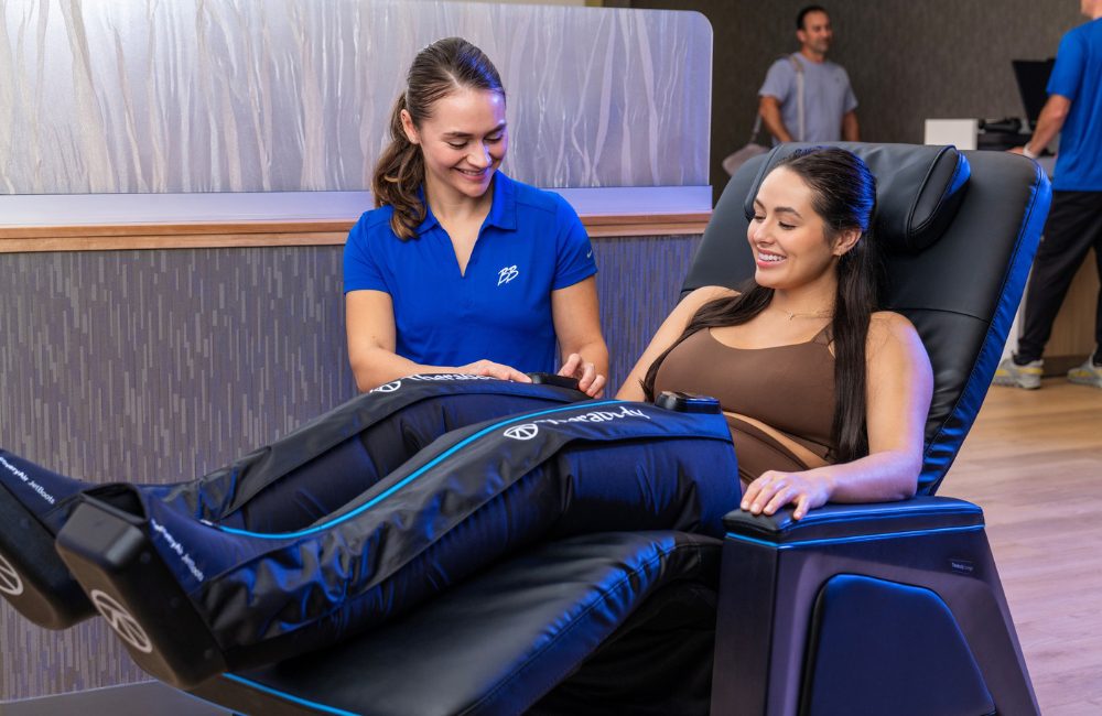 a recover team member assists a gym member with compression therapy during a recovery session at brick bodies gym in padonia